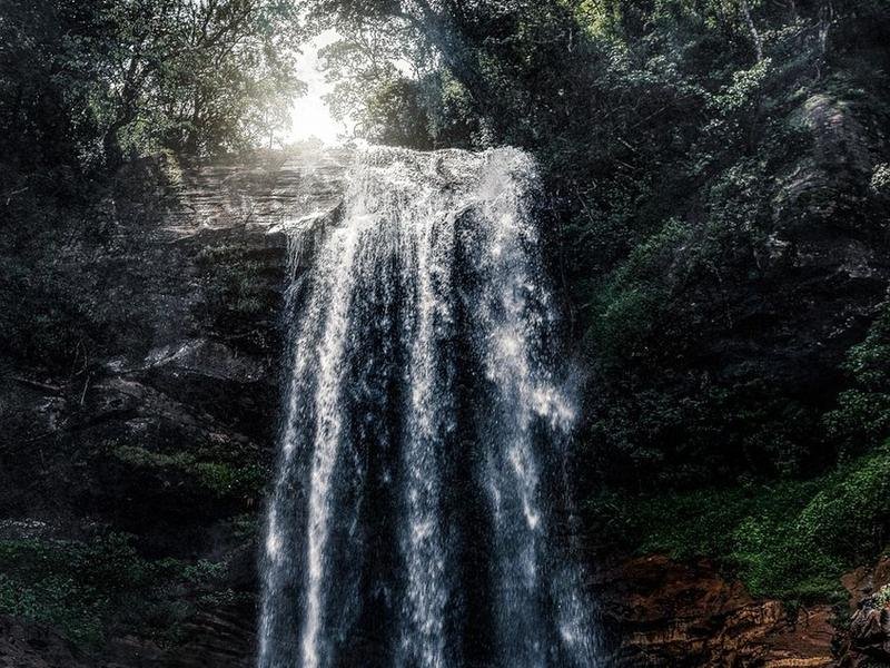 A waterfall dropping through dark forest in Sri Lanka